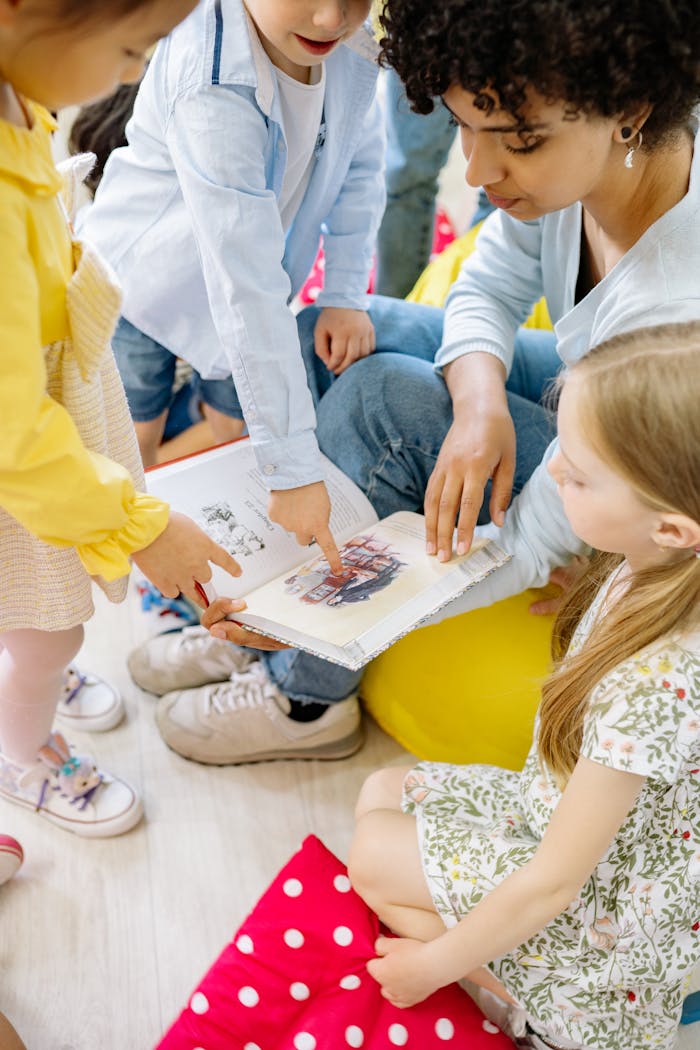 Preschool children gathered around a teacher reading a storybook indoors.